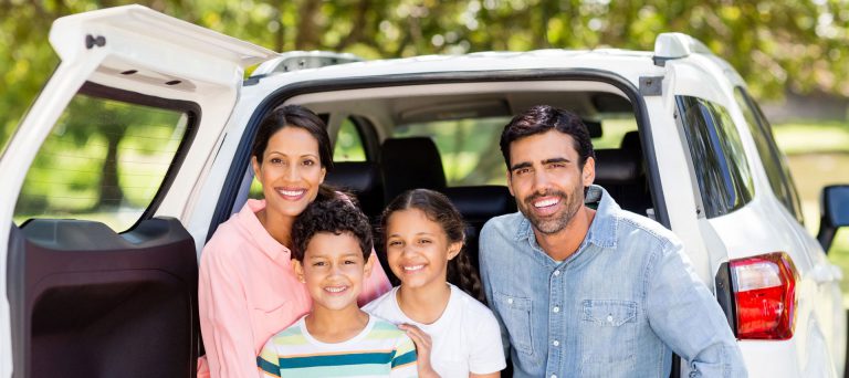 Portrait of a family smiling at the back of their car